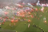 Hundreds of football ultras storm pitch as flare strikes keeper in face before game is abandoned